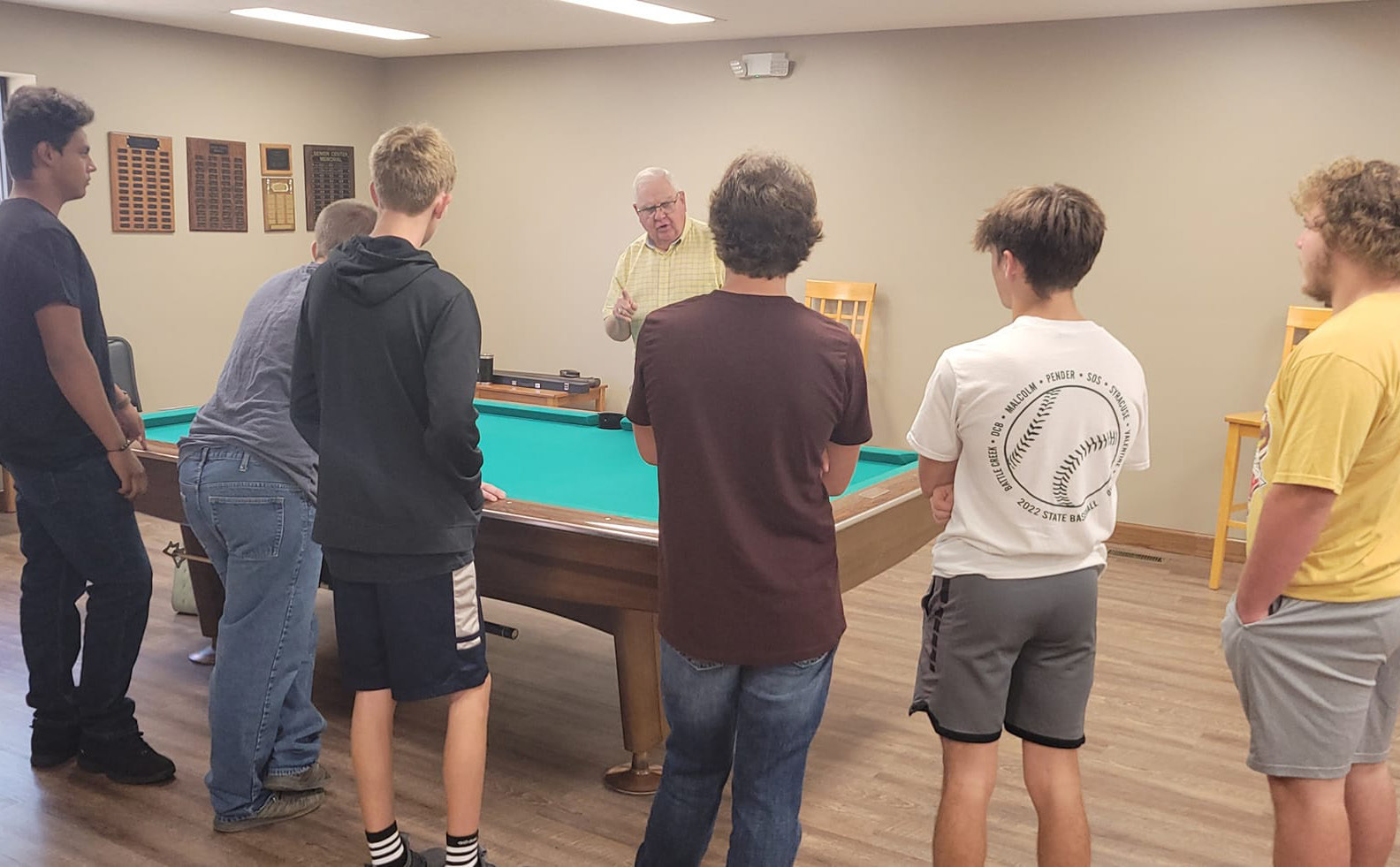 Mrs. Berggren has been taking her P.E. class to the Osceola Senior Center to learn pool (billiards). Here Charles Roberts explains the game to the high school youth. Photo provided.