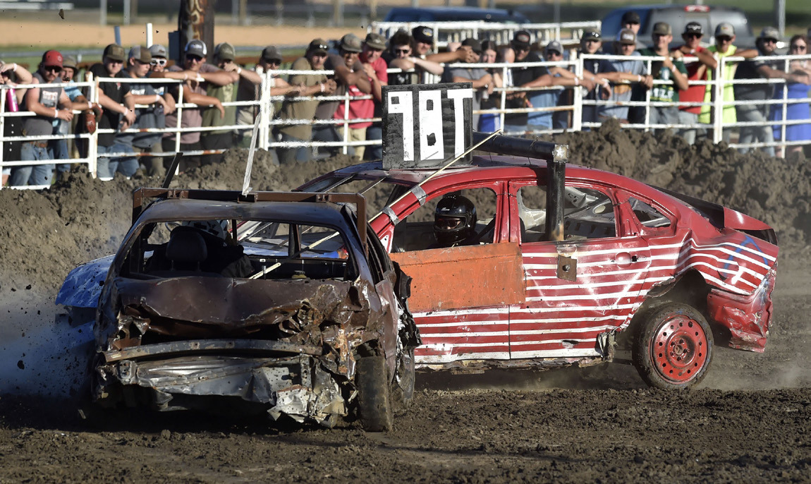 Above: Noah Tworek (98T), of Clarks, tangles with eventual winner Logan Dougherty to capture second place in the Purestock Feature at the Polk County Fair demolition derby. Right: Jason Nuttelman and his son Devin (of Stromsburg) await the verdict as the Limited Weld entry they built undergoes tech inspection before the start of the Polk County Fair demolition derby. Photos by Eric Gregory for the Flatwater Free Press
