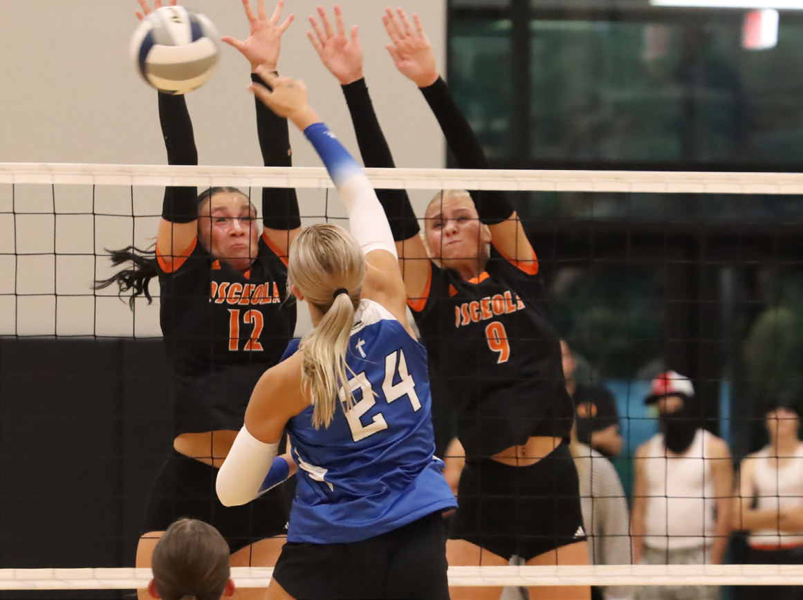 Osceola’s Alexis Burritt (12) and Kenzie Bartling (9) combine for the stuff block on Archangel Catholic’s Whitney Wegener (24). PCN file photo by Ken Kush.