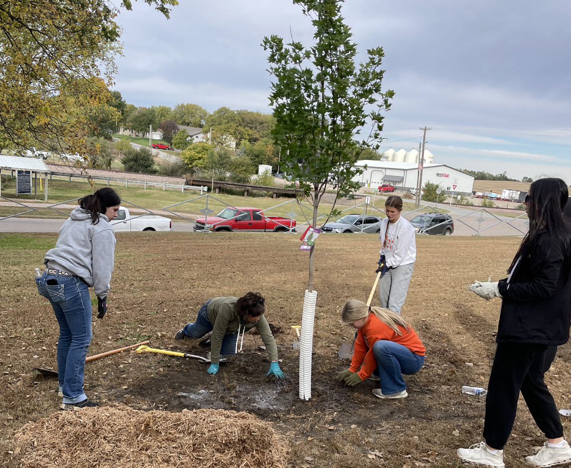 Above: Korrina Niemann, Jenni Harrington, Kinlee Feezell, Halle Gabel, and Camryn Peterson. Jenni assists the group as they prepare to mulch around a freshly planted tree. Photo provided.