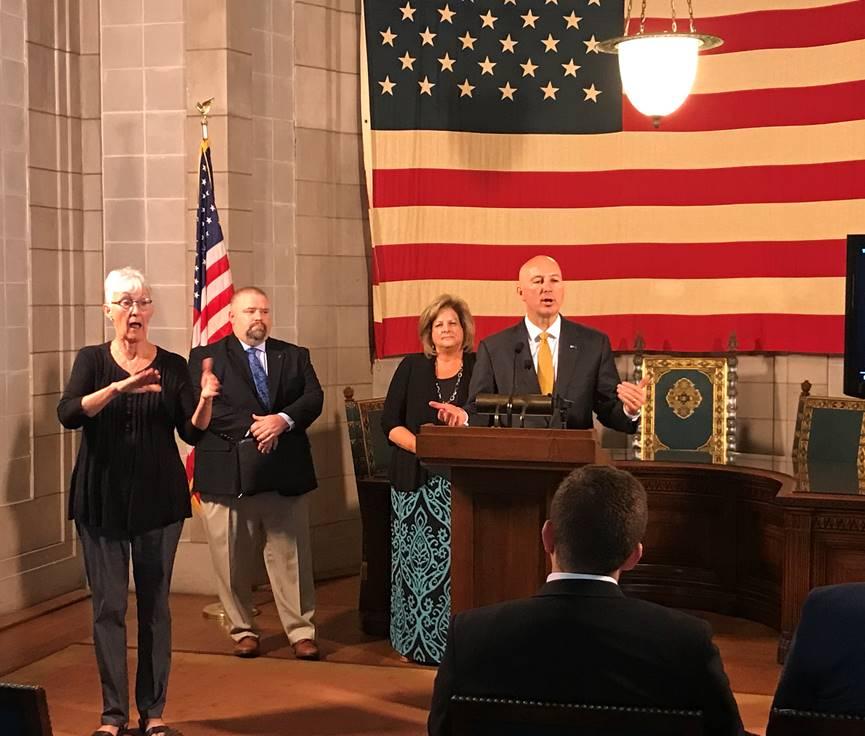 From left to right: ASL interpreter Frances Beaurivage, Kyle Kinney of Boys Town,  DHHS Behavioral Health Director Sheri Dawson, and Gov. Ricketts (podium)