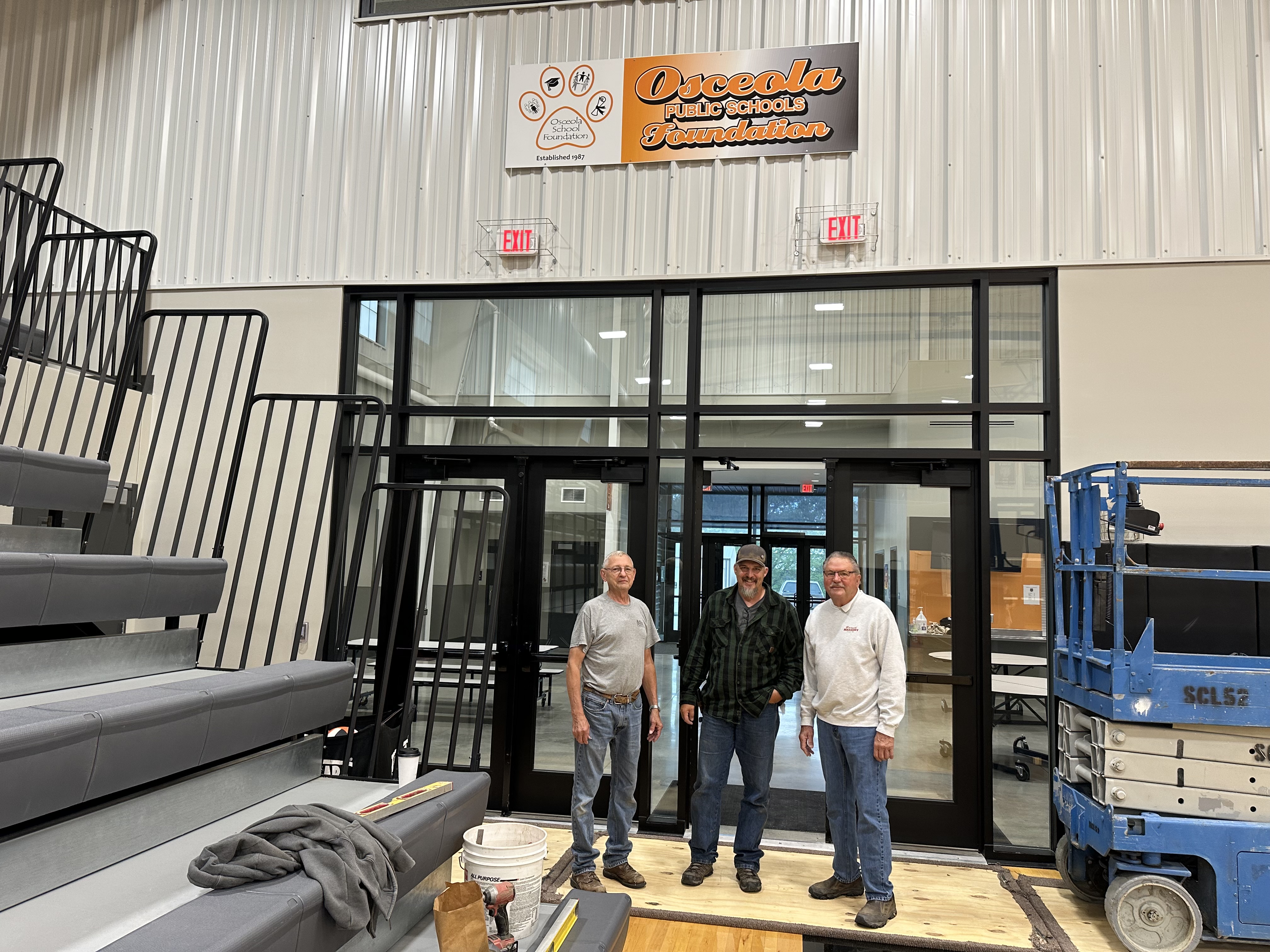 The new Osceola Foundation sign hangs high in the Osceola gym. The three volunteers pictured here (L-R) Jerry Miller, Jesse Pliefke and Ron Boruch installed the sign. Photo was provided.