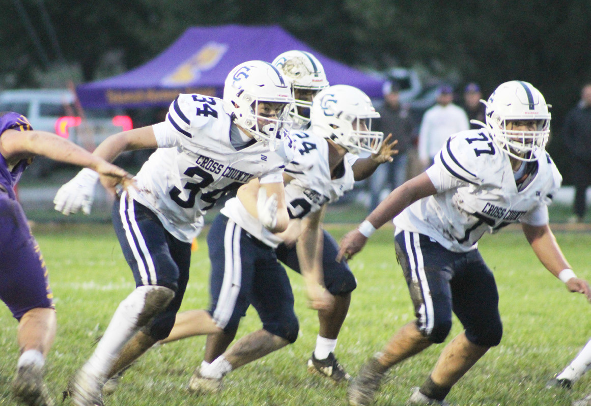 The Cross County Cougars front line of Benson Seim (34), Bode Berggren (24) and Krayton Schoch (77) provide blocking for the Cougars back at Tekemah Herman on Friday night. PCN photo by Trevor Blevins.