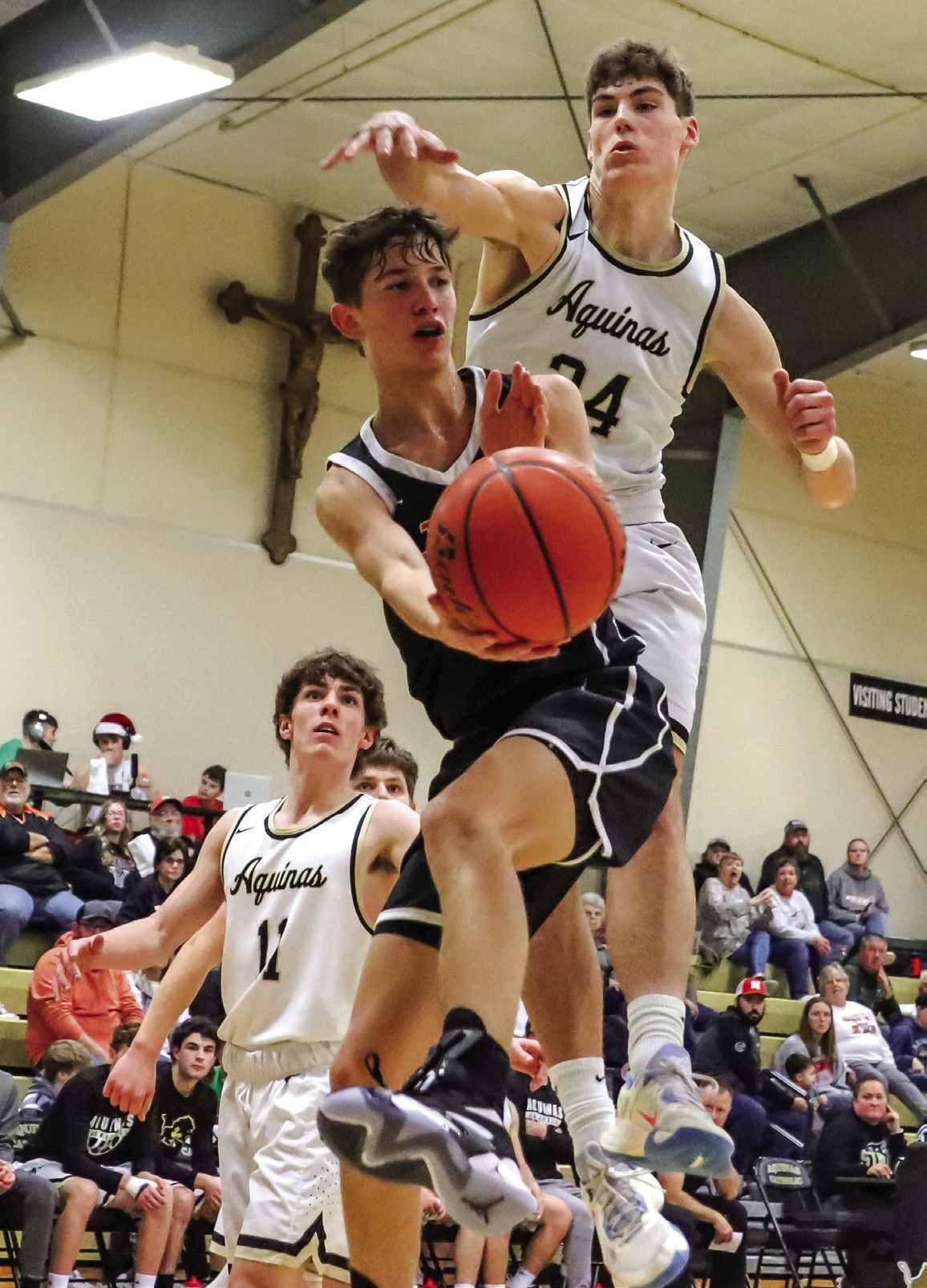 Kelby Neujahr makes a pass under the hoop against DC Aquinas. PCN photo by Blaine Winslow.