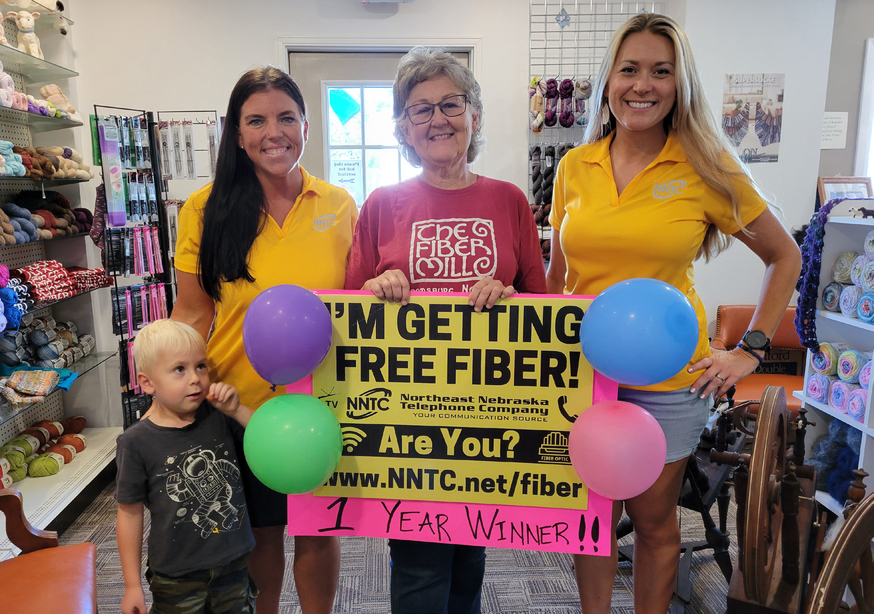 Above: Clare Quandt of Stromsburg won a free year of fiber internet and TV service from NNTC (Northeast Nebraska Telephone Company). She is pictured (center) with grandson Hans (left) and NNTC representatives. PCN Photo by Beth Sparrow.