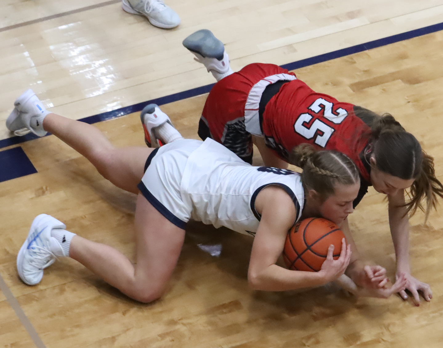 Cross County sophomore Olive Peterson gets control of the loose ball under the basket as she battles with Cozad freshman Ashlyn Propp. Peterson led the Cougars with 13 points. PCN photo by Ken Kush