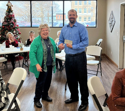 Volunteer Jane Roberts hands CEO Marcus Augustin a check for new chemistry analyzer for the hospital. Photo provided.