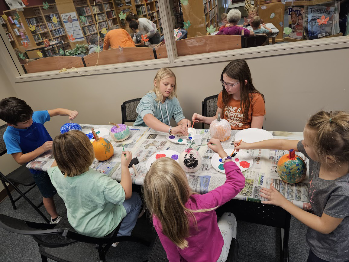 Above: Kids painted pumpkins at the Stromsburg library. Below: Even parents, grandparents and other guardians helped. Photo provided.