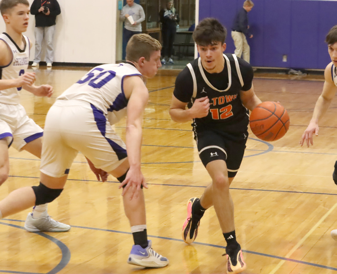 Junior Jackson Winslow (12) tries to get around the defense of Archangels Catholic’s Gage Braun. Winslow led the Bulldogs with 18 points, but it was not enough as Archangels Catholic Defenders defeated Osceola 65-42. PCN photo by Ken Kush.
