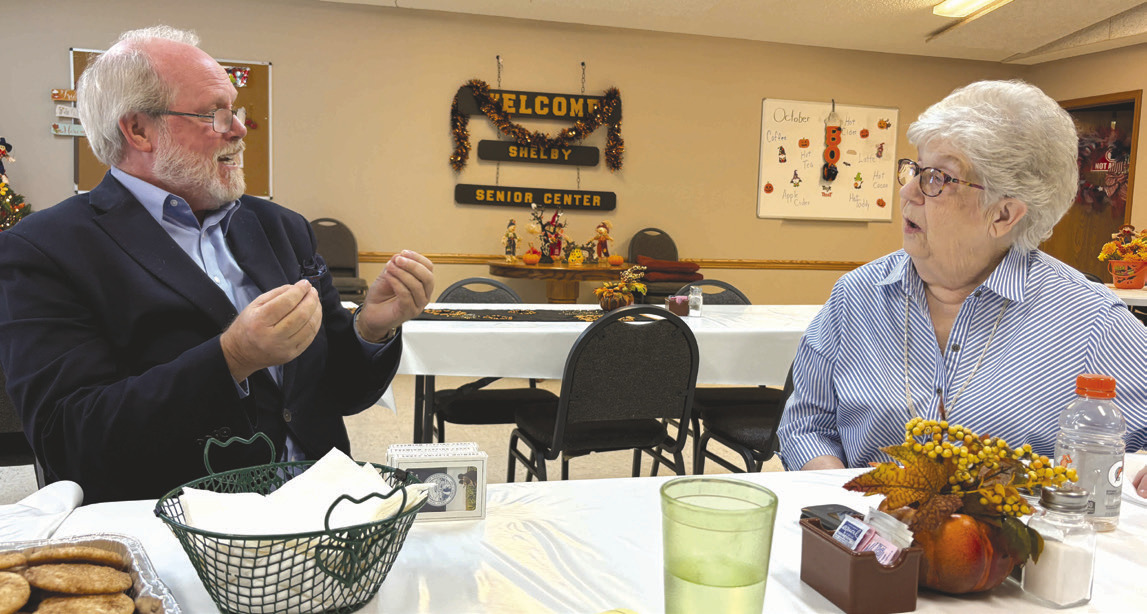 Above: Ryan Southan with the attorney general’s office talks with Patty Teig in Shelby about scams. PCN photo by Beth Sparrow. Below: A group of about 27 came to Polk to hear him speak on the same topic. Photo provided.