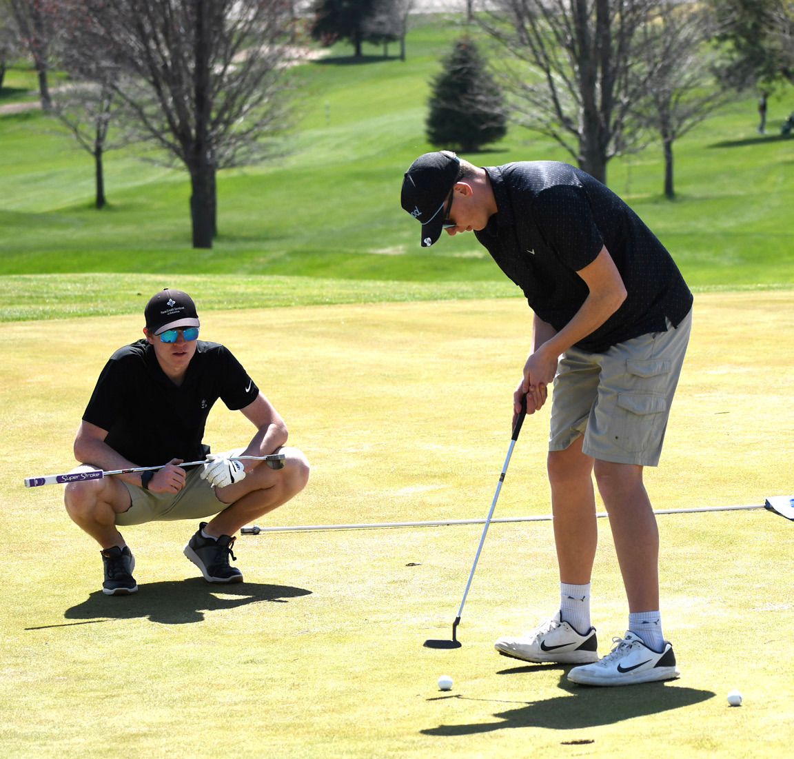 Wyatt Hengelfelt (CC) helps teammate Brock Allen (CC) line up his putt. Photo provided by Emily Blackburn, SRC