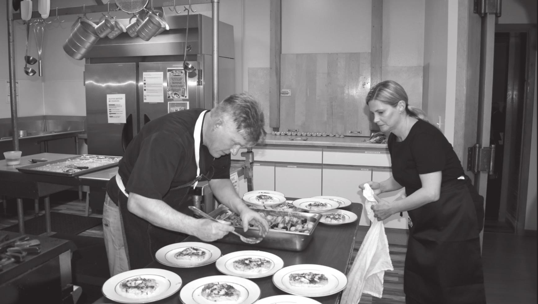 Swedish chef Patrik Landberg and Heather Collins put the finishing touches on the salmon, peas and potatoes at the Swedish dinner Saturday night.