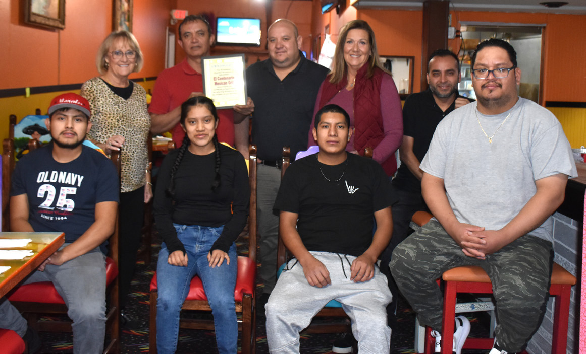 Cinda Koinzan (back left) and Sherry Oberg (back second from right), chamber ambassadors, welcome El Centenario to Stromsburg. Co-owner Jose Leon is in back next to Sherry, and manager Alfredo Gutierrez holds the welcome plaque. PCN photo by Beth Sparrow.