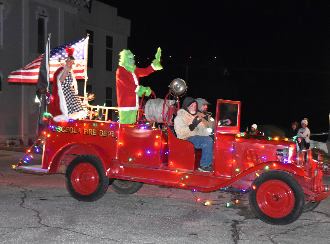 Above: The Grinch came to Osceola and rode in the parade. Below: The cheermeister rode on a trailer in the parade. Far below: People enjoyed popcorn from the pocket park. PCN photos by Beth Sparrow.