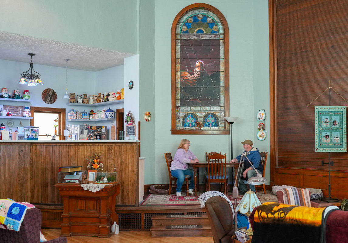 Kathy and Tim Johnson sit at their kitchen table in Benedict. The Johnsons live in the former Zion Evangelical Lutheran Church. The high ceilings and stained-glass windows were overwhelming at first, but now they enjoy the unique features. Photo by Naomi Delkamiller/Flatwater Free Press