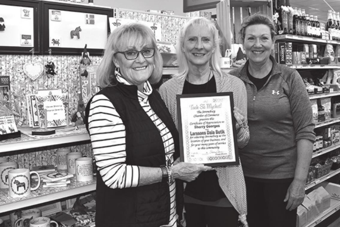 Chamber ambassadors Cinda Koinzan (left) and Sherry Oberg (right) present Sherri Georges, owner of Larsson’s Dala Butik with a certificate of appreciation.