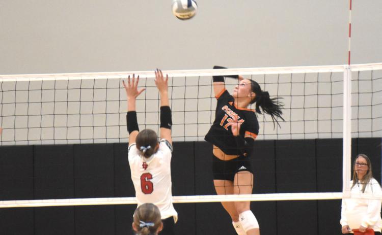 Junior Alexis Burritt (12) attacks over the Doniphan-Trumbull block in last Thursday’s game at Osceola High School. PCN photo by Beth Sparrow.