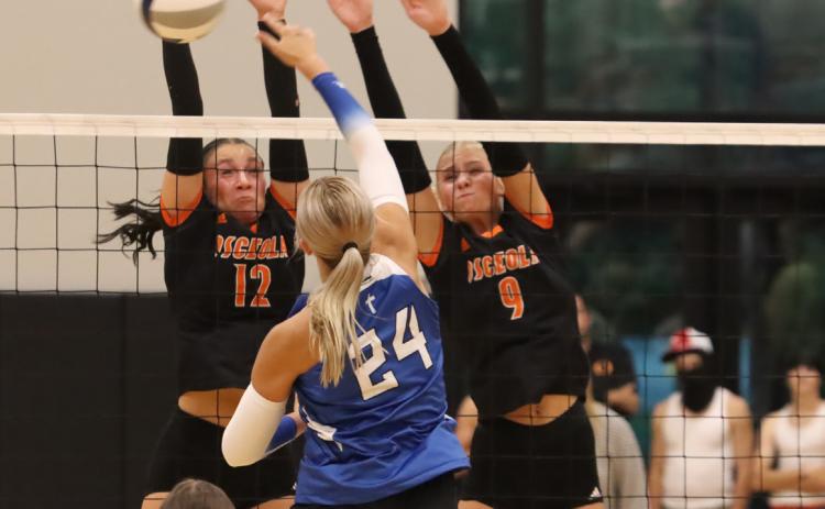 Osceola’s Alexis Burritt (12) and Kenzie Bartling (9) combine for the stuff block on Archangel Catholic’s Whitney Wegener (24). PCN file photo by Ken Kush.