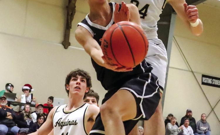 Kelby Neujahr makes a pass under the hoop against DC Aquinas. PCN photo by Blaine Winslow.