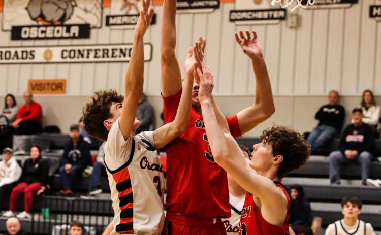 Osceola sophomore Landan Drozd (3) mixes it up with a couple of David City players as he battles for the rebound. PCN photo by Blaine Winslow.