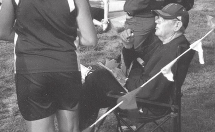 You can usually find Cougar discus coach Rich Owens watching his athletes from a chair by the throwing circle. Here, he talks to Ellie Pinley after she threw in a meet last spring.