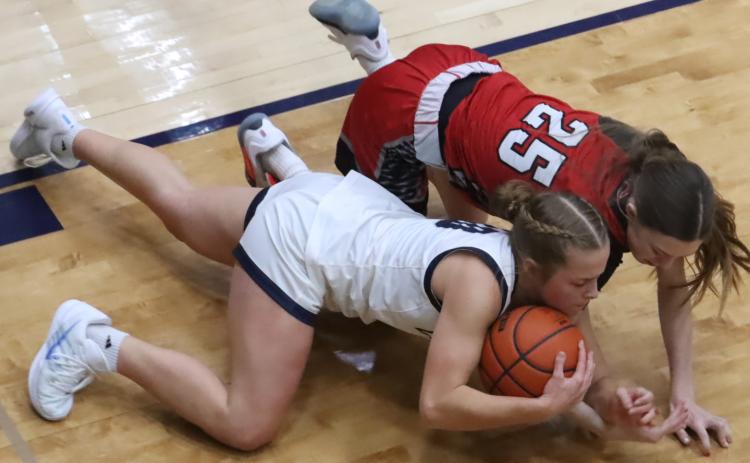 Cross County sophomore Olive Peterson gets control of the loose ball under the basket as she battles with Cozad freshman Ashlyn Propp. Peterson led the Cougars with 13 points. PCN photo by Ken Kush