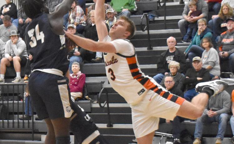 Osceola's Isaiah Zelasney uses acrobatic moves to get to the basket despite strong defense from Cross County's James Elgin. PCN photo by Beth Sparrow