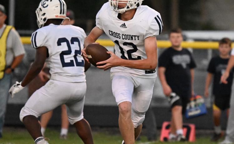 Cross County senior quarterback Sawyer Anderson (12) rolls out to his left as he looks for an open receiver. Anderson threw for 197 yards as he set a new school record in 11-man football. Photo provided by Michael Happ of the St. Paul Phonograph Herald.