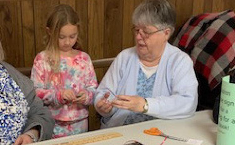 Louise Logston helps Ava Mescher make her craft from the library on Sunday afternoon. Photo provided by Becky Carlstrom