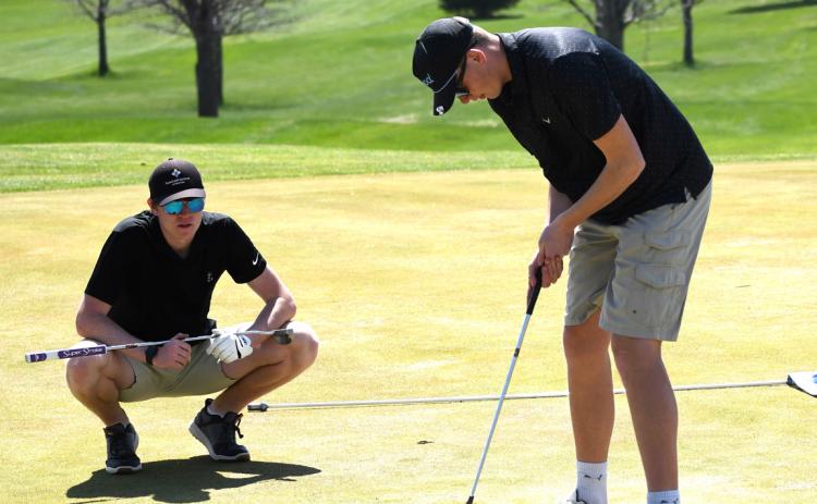 Wyatt Hengelfelt (CC) helps teammate Brock Allen (CC) line up his putt. Photo provided by Emily Blackburn, SRC