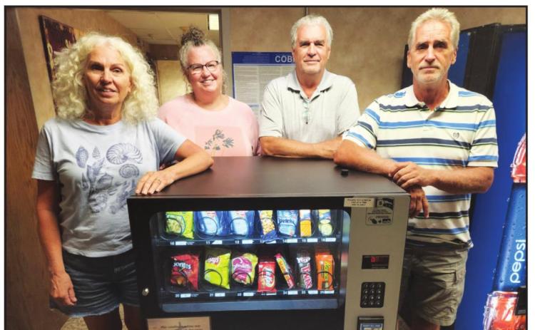 Marta Papik, Lisa Wyrick, Mark Erickson and Scott Erickson stand by the vending machine donated by the Erickson family.