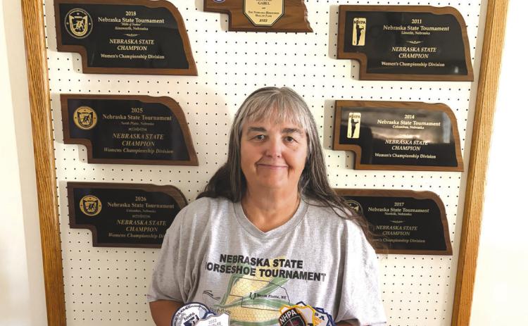Above: Krystal Gabel of Shelby is pictured with her many plaques in horseshoes, including state champion for six years. She also holds patches of her other accomplishments. Photo provided.
