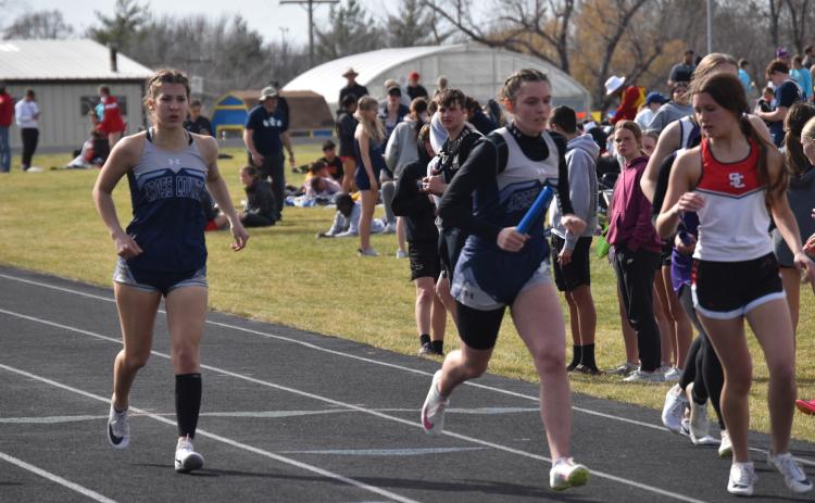 Lindee Kelley (CC) takes the baton from Ella Clark (CC) in the 4x400 relay. PCN photo by Cienna Friesen.