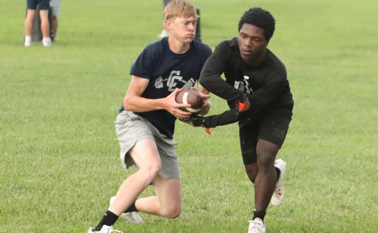 Cross County senior quarterback Sawyer Anderson pulls the ball back from running back Tyion Francis during the Cougars final summer practice. PCN photo by Ken Kush