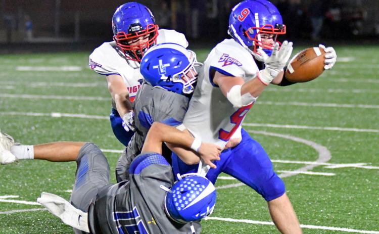 Wyatt Urkoski carries the ball down field while being tackled by two Knight defenders. Photo courtesy of Richard Rhoden of Aurora News-Register.