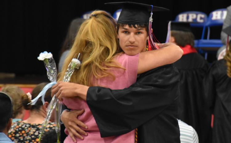 Levi Russell gives a hug at graduation on Saturday. Below all 13 graduating seniors sit on the stage during the commencement at High Plains. PCN photos by Beth Sparrow.