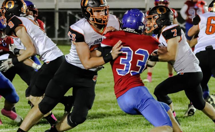 Creighton Sterup (OSC #53) blocks Carter Urkoski (HPC #33) so Matt DeMers (OSC #7) can run the ball. PCN photo by Blaine Winslow.