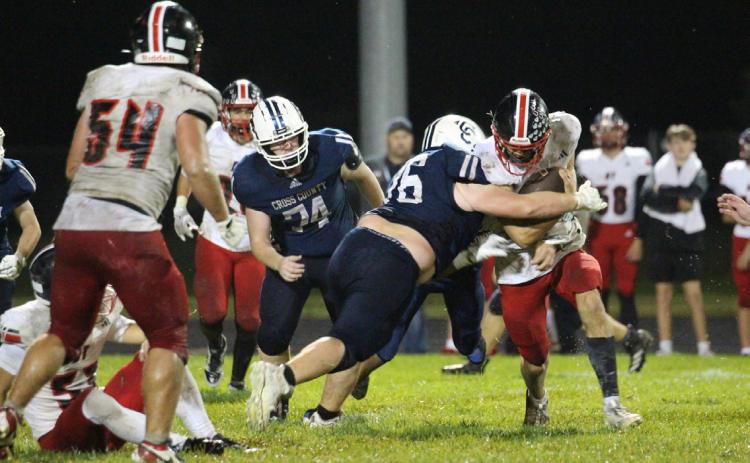 Cross County senior defensive lineman Jacob Smith (76) wraps up the Doniphan-Trumbull runner in action from last Friday’s homecoming game. Photo by Travis Lane.